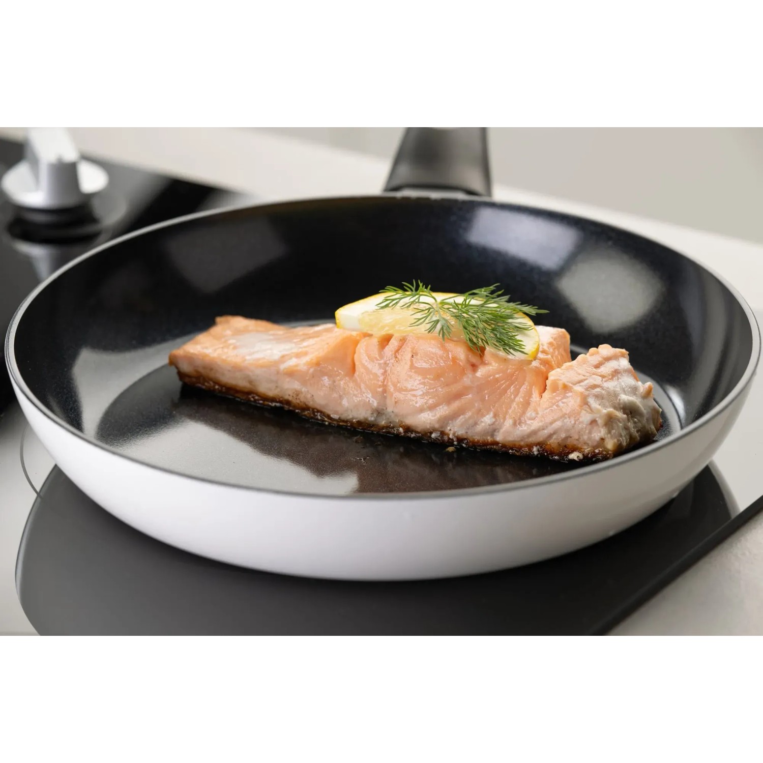 Fackelmann Arcadalina Pfanne (24 cm) mit Lachsfilet und Zitrone auf einem Induktionsherd.