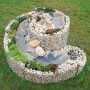 Bellissa Gabionen-Kräuterspirale Groß, gefüllt mit Steinen und bepflanzt.