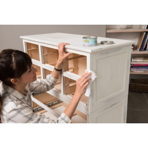 Frau bearbeitet Kommode mit Bondex Kreidefarbe Weiß und Lappen für Shabby Chic Look.
