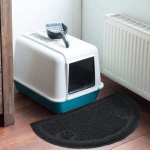 Schwarze, halbrunde Relaxdays Katzenklo Matte aus PVC mit Pfoten-Motiv vor einer Katzentoilette. Rutschfest für Sauberkeit.
