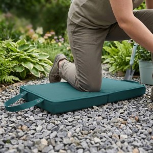Dunkelgrüne, stoßdämpfende Kniematte für Gartenarbeit. Eine Person kniet auf der faltbaren Knieschutzmatte auf Kies im Garten.