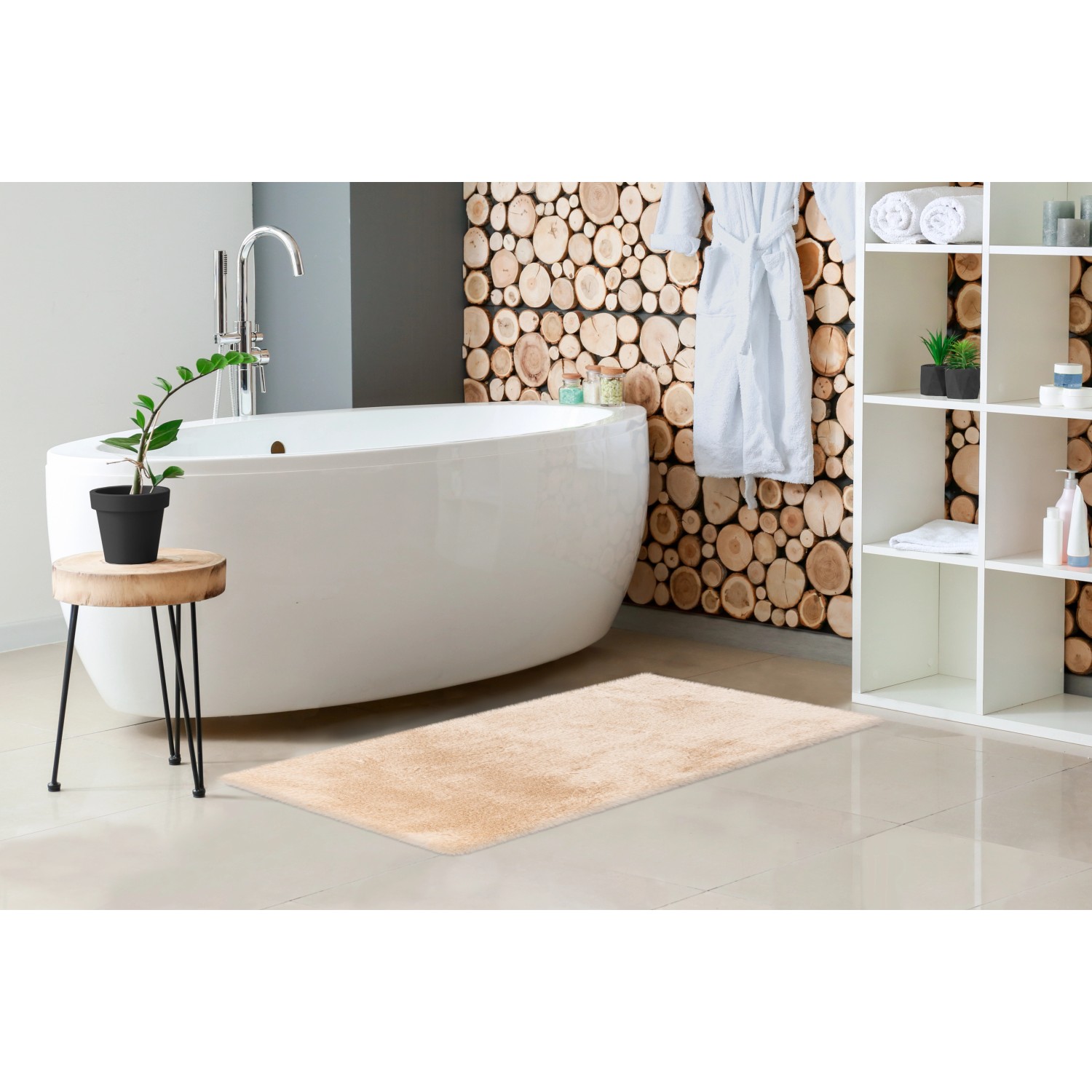 Beiger Lalee Badteppich Heaven, 40x60 cm, im Badezimmer mit Badewanne und Regal.