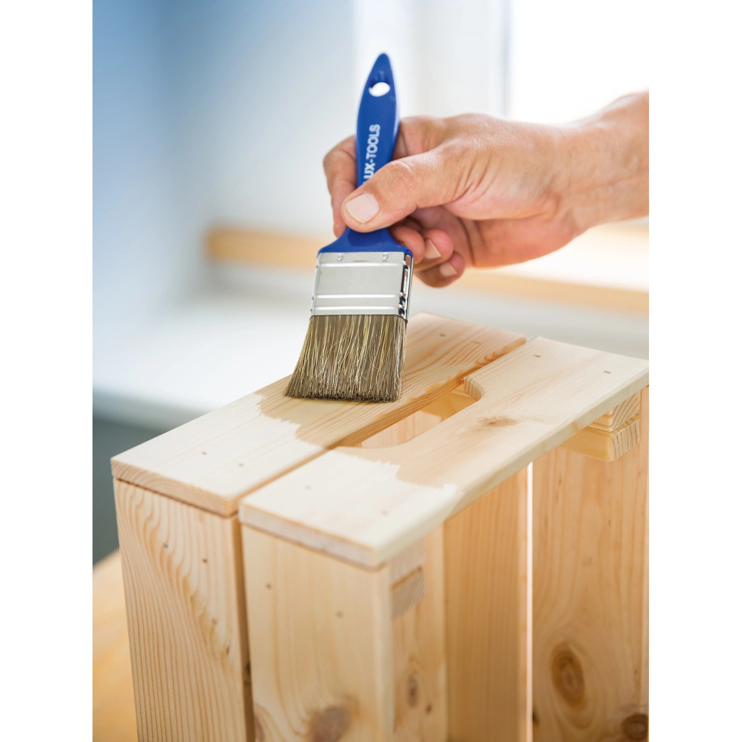 Hand lasiert Holzkiste mit LUX Flachpinsel Lasur 30mm. Pinsel mit blauem Griff.