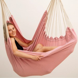 AMANKA XXL Hängesessel rosa: Frau entspannt in großer Stoff-Hängematte mit Spreizstab.