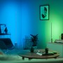 Philips Hue Gradient Signe Stehleuchte in Weiß, die farbiges Licht an die Wand wirft.