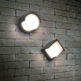 Zwei moderne, mattschwarze Reality LED-Außenwandleuchten Puno an einer Backsteinwand.