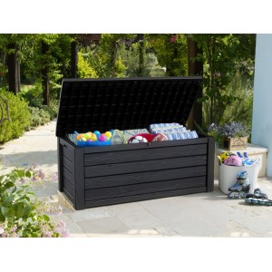 Geöffnete Keter Eastwood Gartenbox 570L in Anthrazit mit Gartengeräte, Kissen und Spielzeug im Garten.