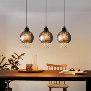 Drei moderne NETTLIFE Pendelleuchten mit rauchgrauen Glasschirmen und funkelnden Kristallanhängern über einem Esstisch. Ideal für Wohnzimmer.