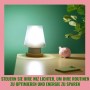 WiZ LED Lampe E27 in Glühlampenform, 4,3W, 903lm, Weiß, auf Nachttisch mit Sparschwein.