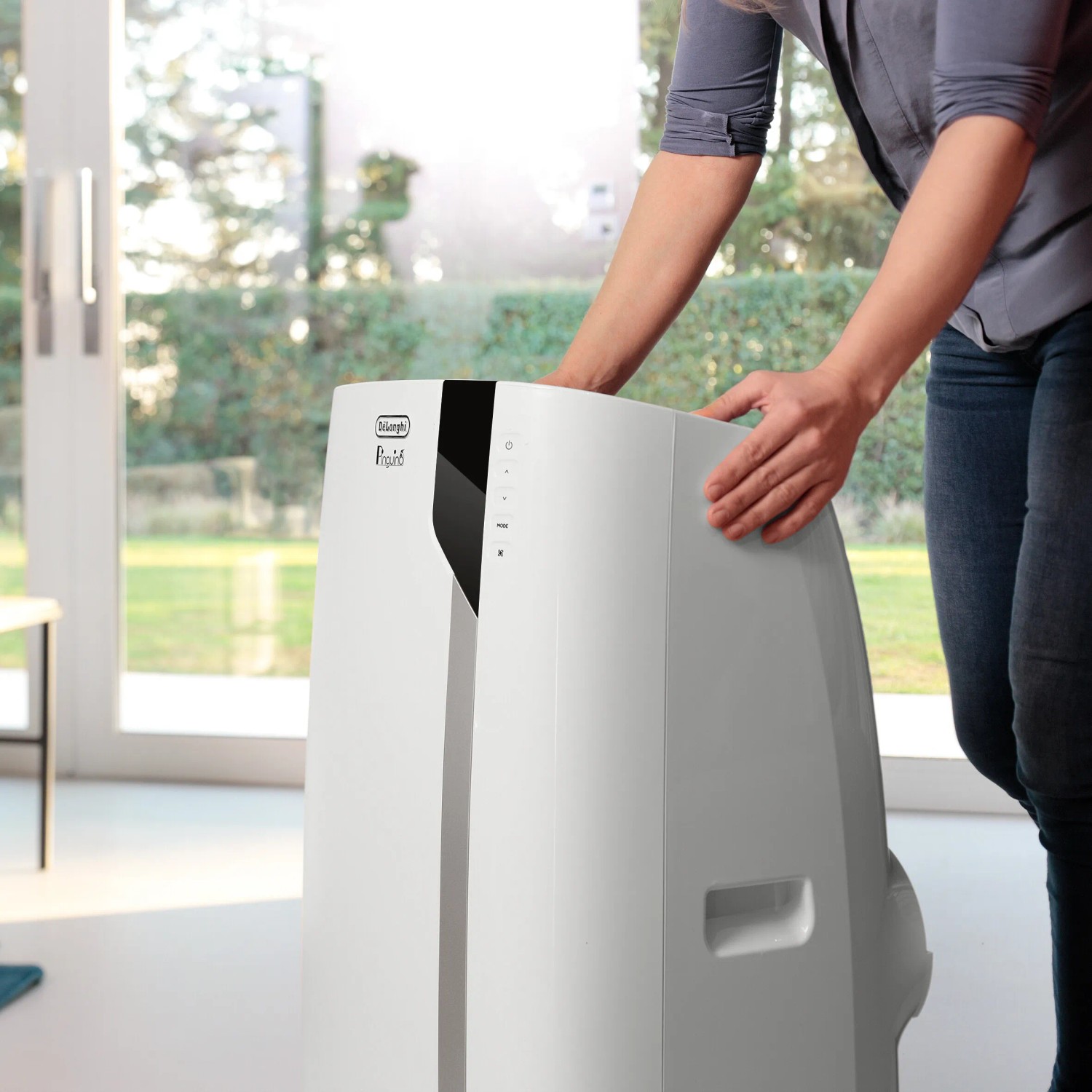 Mobiles DeLonghi Klimagerät Pinguino Extreme PAC EX93 in Weiß, wird von einer Person bewegt.