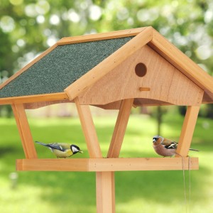 Vogelfutterhaus aus Tannenholz mit Ständer und grünem Dach. Zwei Vögel fressen.