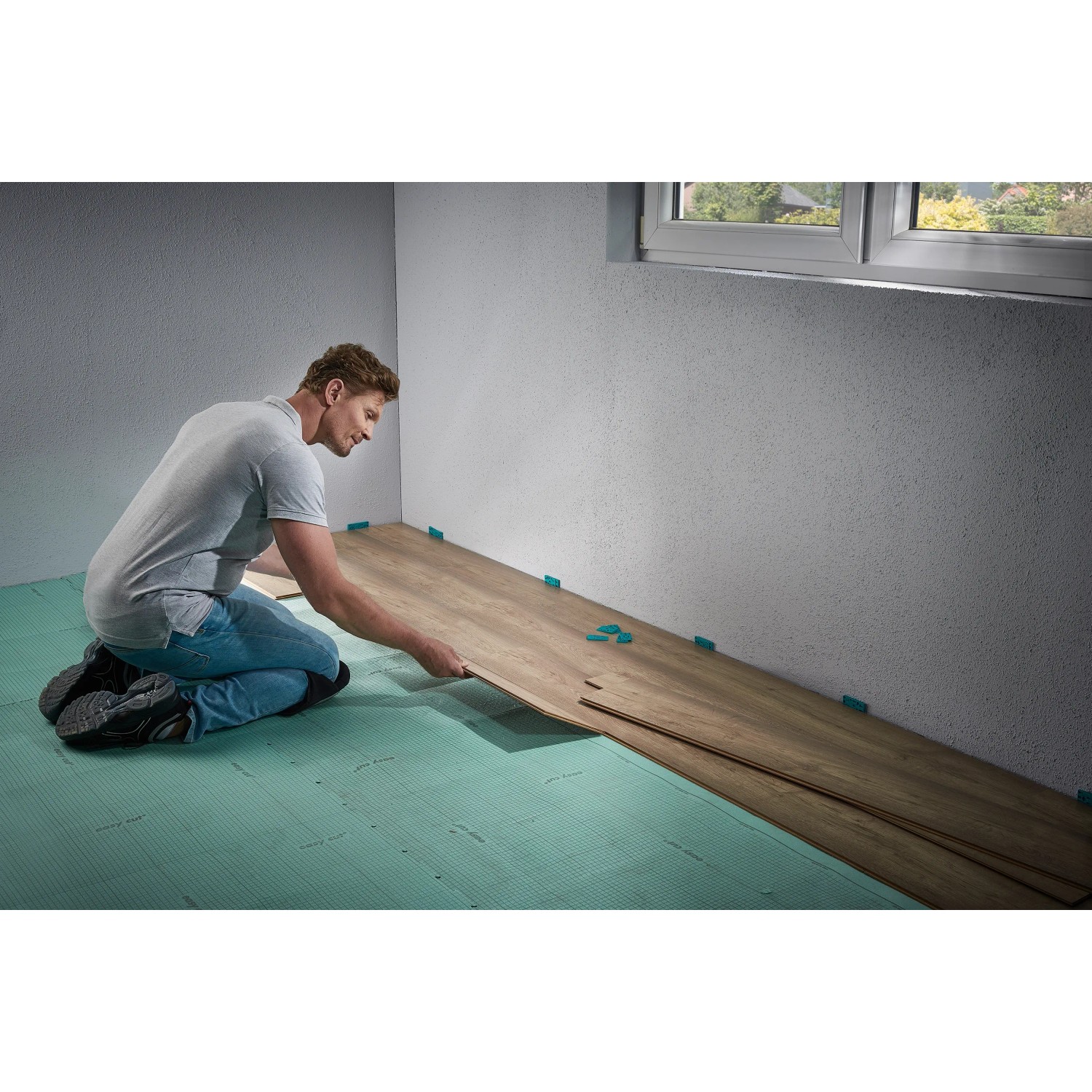 Mann verlegt Laminat mit wolfcraft Einpass-Set für Laminat- und Designboden.
