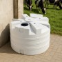 Weißer KMND 5000L Trinkwasser Wassertank aus PE im Außenbereich, auf Pflastersteinen, mit Kühen im Hintergrund.