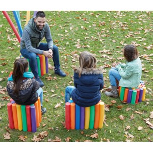 Personen sitzen auf Hockern aus bunten Comfy Schwimmnudeln im Garten.