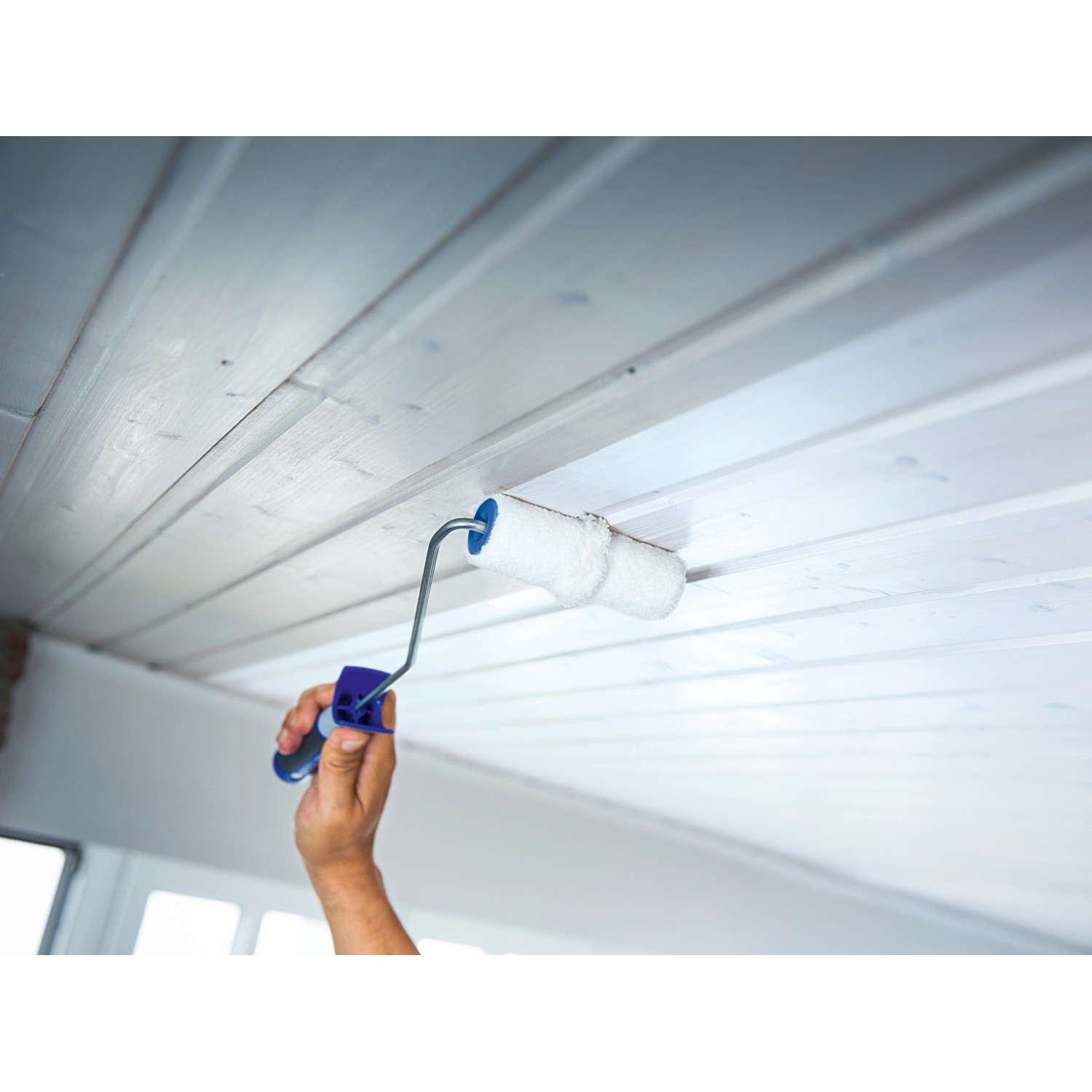 LUX Panel-Roller 12 cm im Einsatz: Hand streicht weiße Holzdecke mit Farbroller.