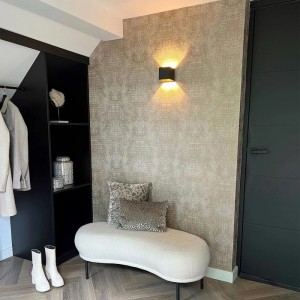 Moderne schwarze QAZQA Wandleuchte Transfer mit Up-Down-Lichteffekt an beiger Wand im Flur.
