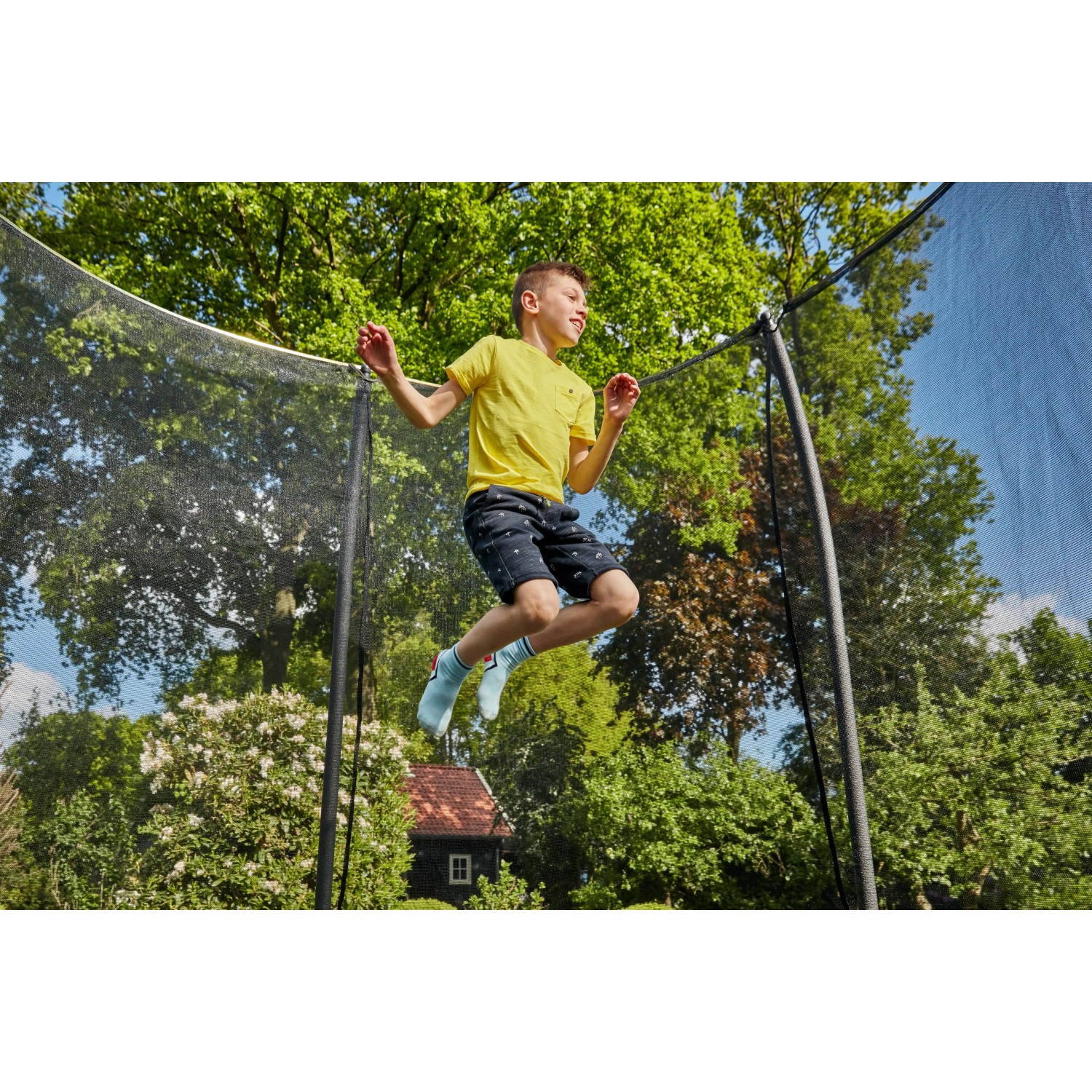 Junge springt auf schwarzem Salta Gartentrampolin Comfort Edition mit Sicherheitsnetz.