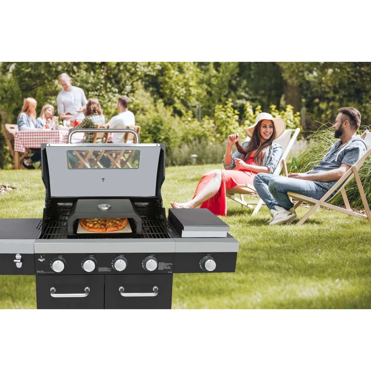 EL Fuego Pizzaaufsatz auf Grill mit Pizza, im Garten mit entspannten Personen.