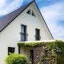 Moderner anthrazitfarbener Französischer Balkon mit vertikalen Füllstäben an weißer Hausfassade. Robustes Geländer.