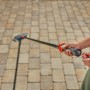 Gardena Cleansystem Stielbürste Hard mit Schlauchanschluss im Einsatz zur Reinigung von Pflastersteinen.