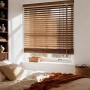 Holzjalousie in Walnussholzoptik am Fenster im Schlafzimmer. 35mm Lamellen filtern Sonnenlicht für gemütliche Atmosphäre.