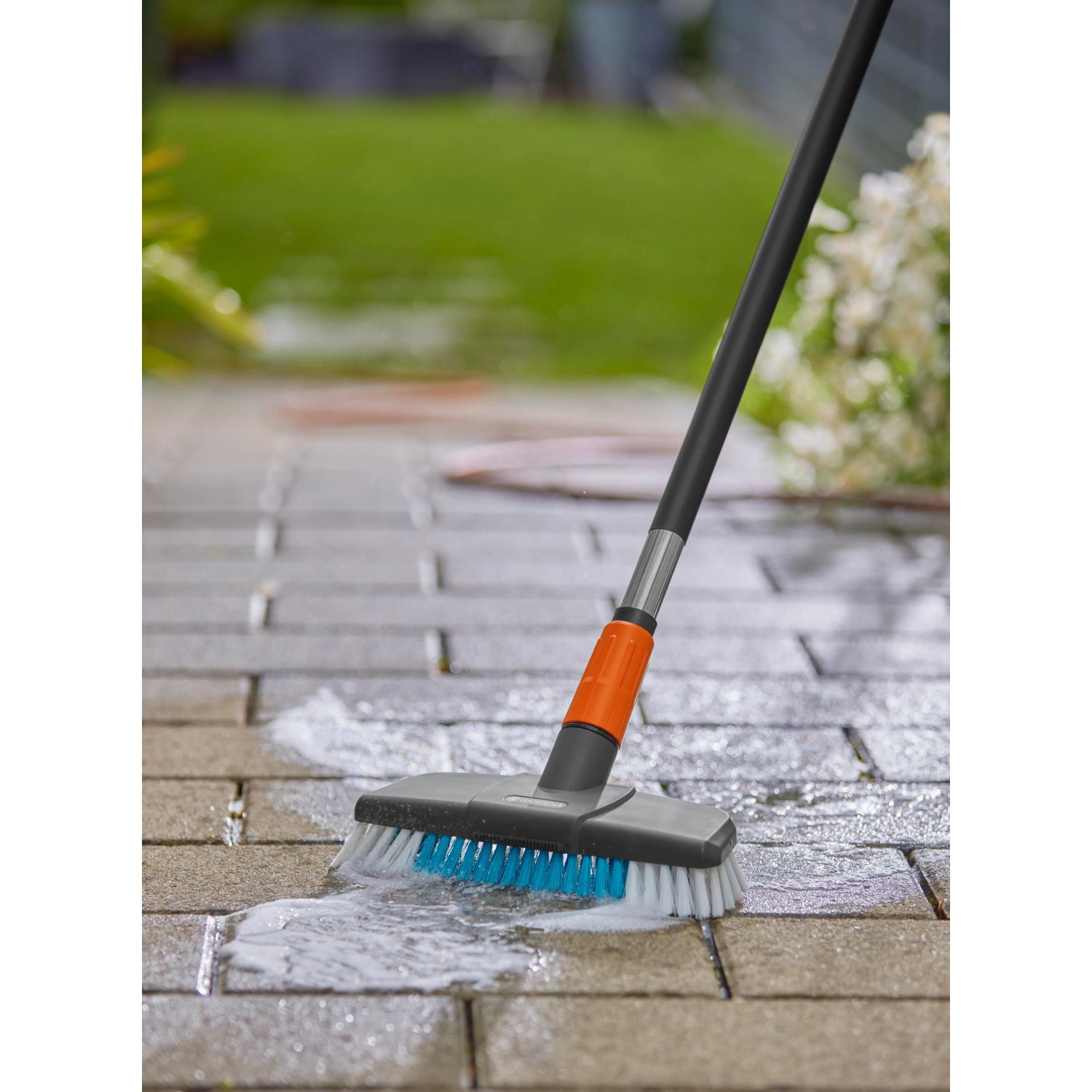 Gardena Cleansystem Stielbürste Hard in Aktion: Pflasterreinigung mit Wasser und Bürste.