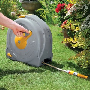 Hozelock Schlauchtrommel Fast Reel mit 40m Schlauch auf Rasen, Hand an Kurbel.