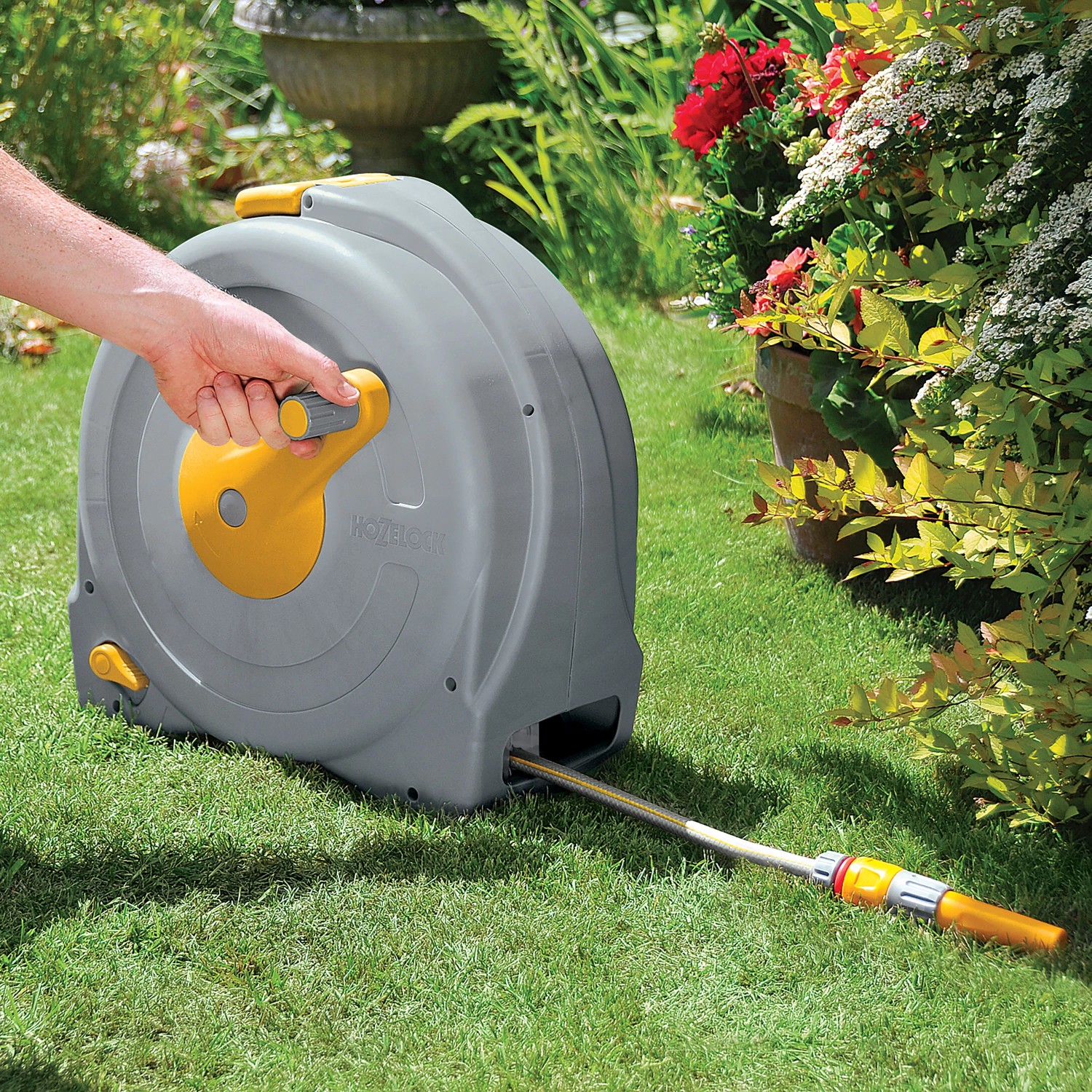 Hozelock Schlauchtrommel Fast Reel mit 40m Schlauch auf Rasen, Hand an Kurbel.