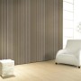 Glööckler Vliestapete Imperial Welle Goldmetallic im Raum mit Sessel und Lampe.
