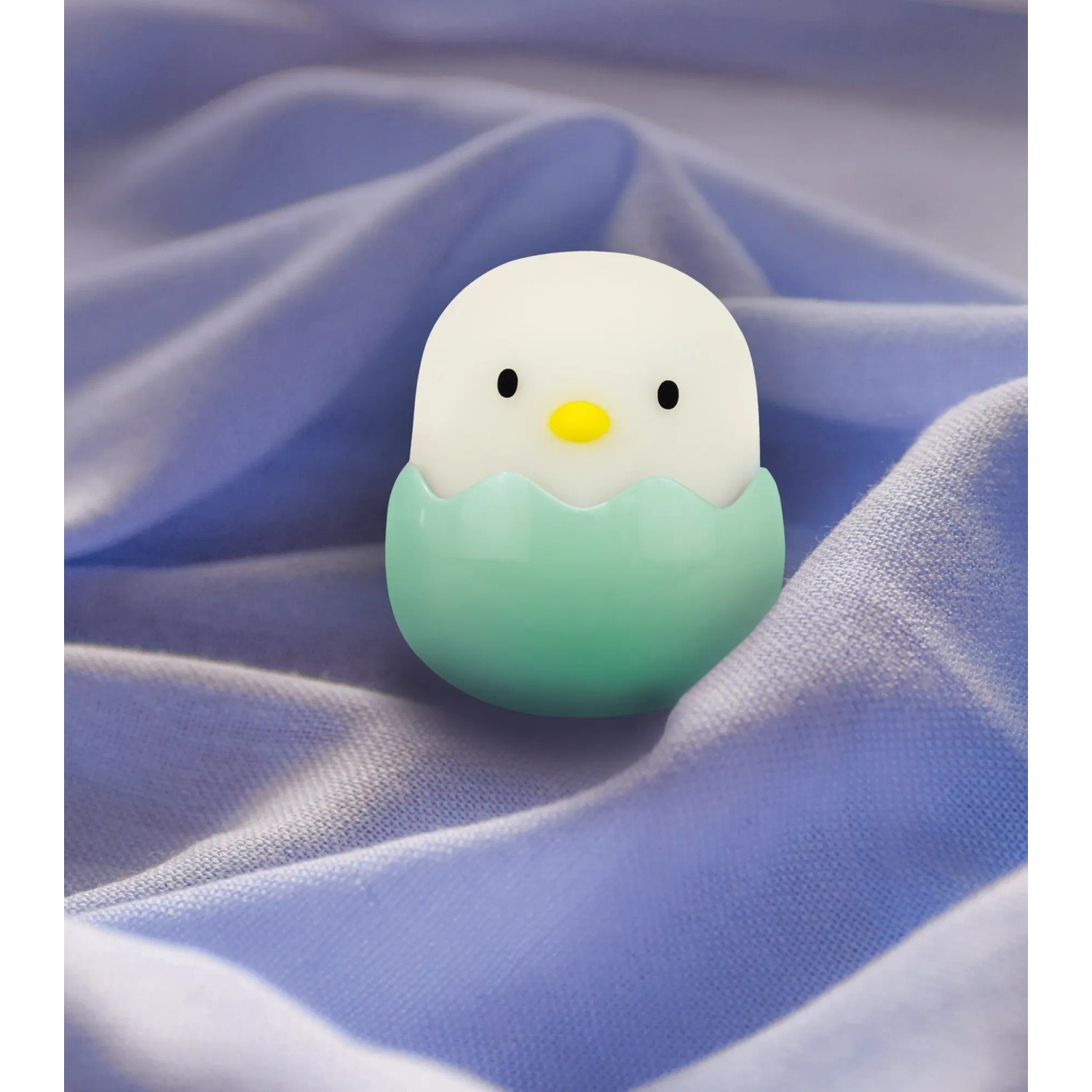 Grünes MegaLight LED-Nachtlicht Baby Eggy mit Akku auf blauem Stoff.