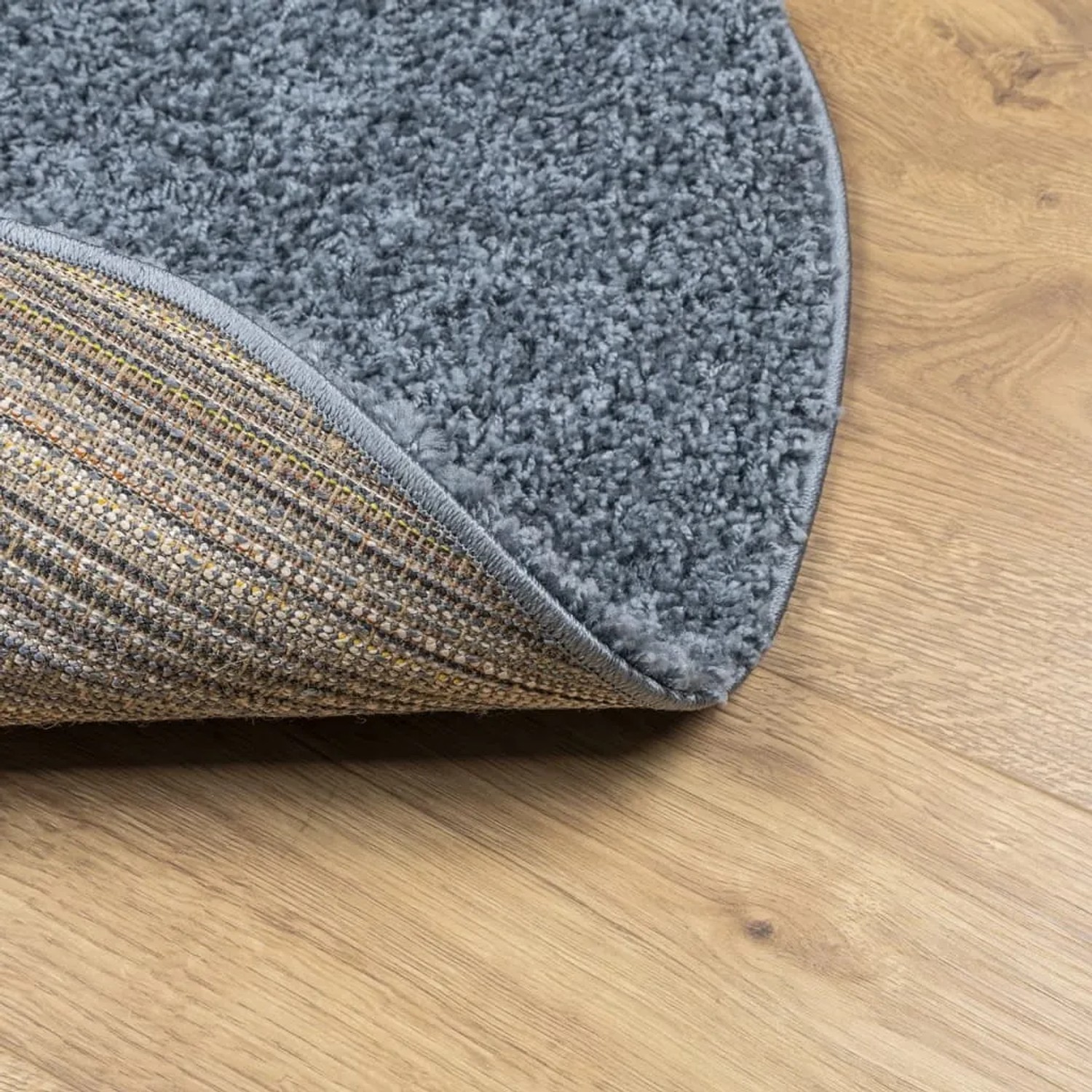 Blauer, runder Shaggy Teppich (Ø 100 cm) mit hochflorigem Flor. Detailaufnahme der Teppichrückseite.