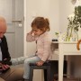 Szene: Vater zieht Tochter im Flur die Schuhe an, warmes Licht.