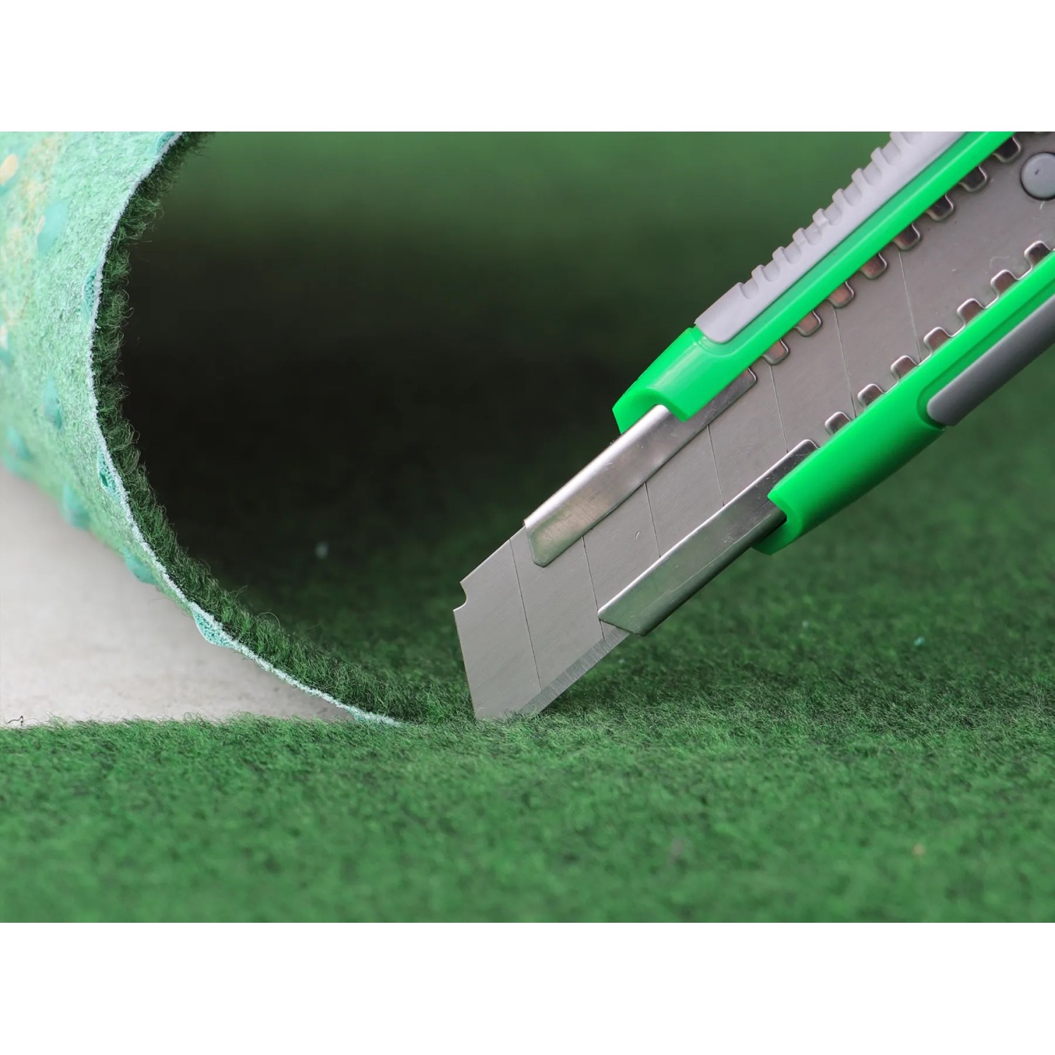 Zuschneiden des braunen Primaflor Rasenteppich Comfort mit einem Cuttermesser.