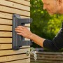 Gardena Wand-Schlauchbox XL an Holzwand mit Hand, Wasserhahn im Garten.