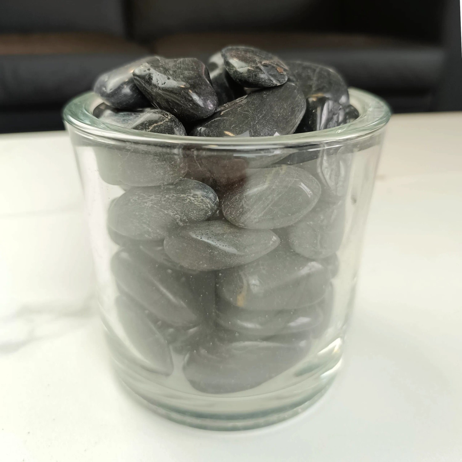 Nahaufnahme von polierten, schwarzen Zierkies-Dekosteinen (2-3 cm) in einem Glas.