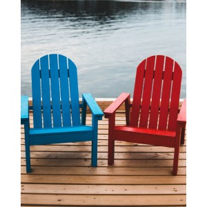 Zwei farbige Holzstühle (blau, rot) auf einer Holzterrasse am Wasser, lackiert mit Acryllack.