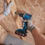 Blauer Bosch Professional Akku-Bohrschrauber GSR18V-52 bohrt in Holz. Hände mit Handschuhen halten den 18V Akkuschrauber.