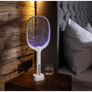 Windhager Fliegenklatsche 2-in-1 elektrisch mit UV-Licht in Ladestation auf Nachttisch.