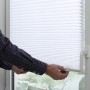 Weißes Gardinia Plissee Solo mit Saugnäpfen am Fenster, Bedienung durch eine Person.