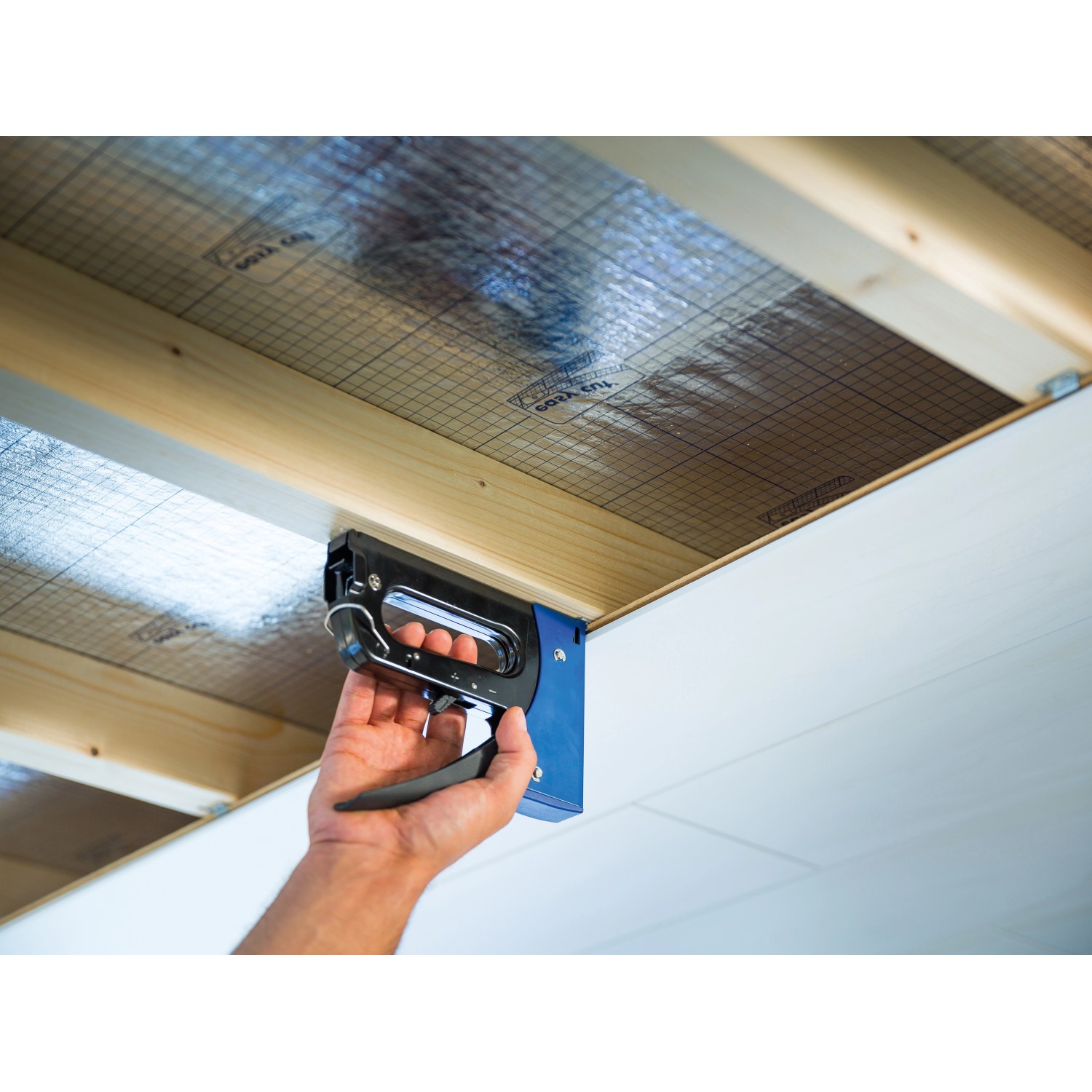 Handtacker von LUX beim Befestigen von Isoliermaterial an einer Decke.