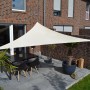 Hell elfenbeinfarbenes Dreiecksonnensegel 360 cm über einer Terrasse mit Tisch und Stühlen.