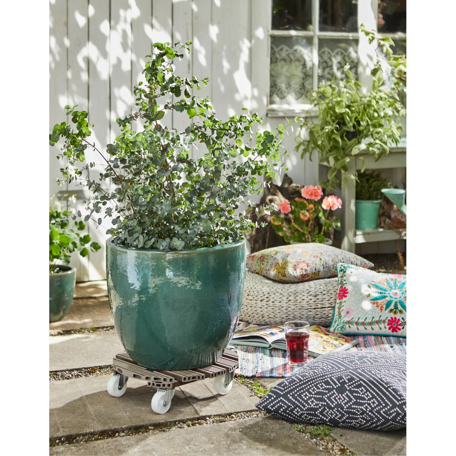 Taupefarbener Wagner WPC Pflanzenroller Ø 38,5 cm mit Pflanze im Garten.