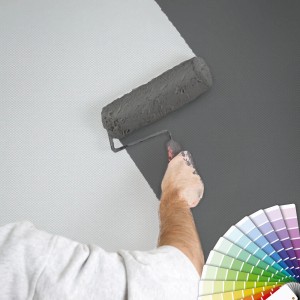 Überstreichbare Vliestapete wird mit Farbrolle grau gestrichen, Farbfächer im Bild.