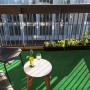 Grüner Primaflor Rasenteppich Park auf einem Balkon mit Tisch, Stühlen und Dekoration.