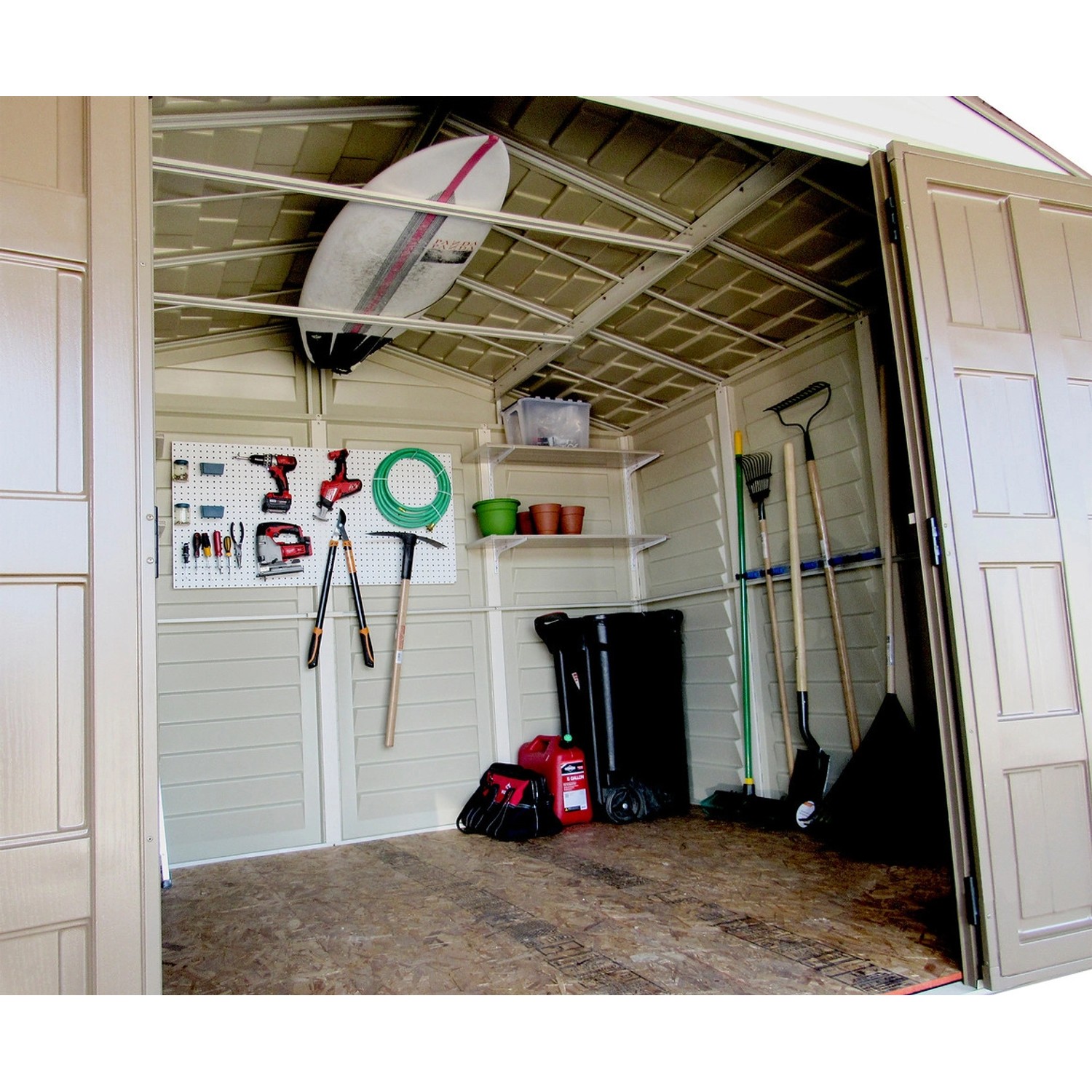 Innenansicht Duramax Kunststoff-Gartenhaus WoodBridge Plus (7,6 m²) mit Gartengeräten und Surfbrett.