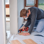 Einhell Multitool-Set im Einsatz: Mann schneidet Holz mit Multifunktionswerkzeug. Zubehör für Multifunktionswerkzeuge.