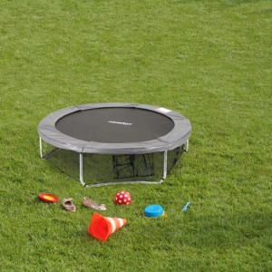 Schwarzes Relaxdays Rahmennetz aus PE am runden Trampolin auf grünem Rasen. Bodensicherungsnetz mit Taschen für Trampolin-Zubehör.
