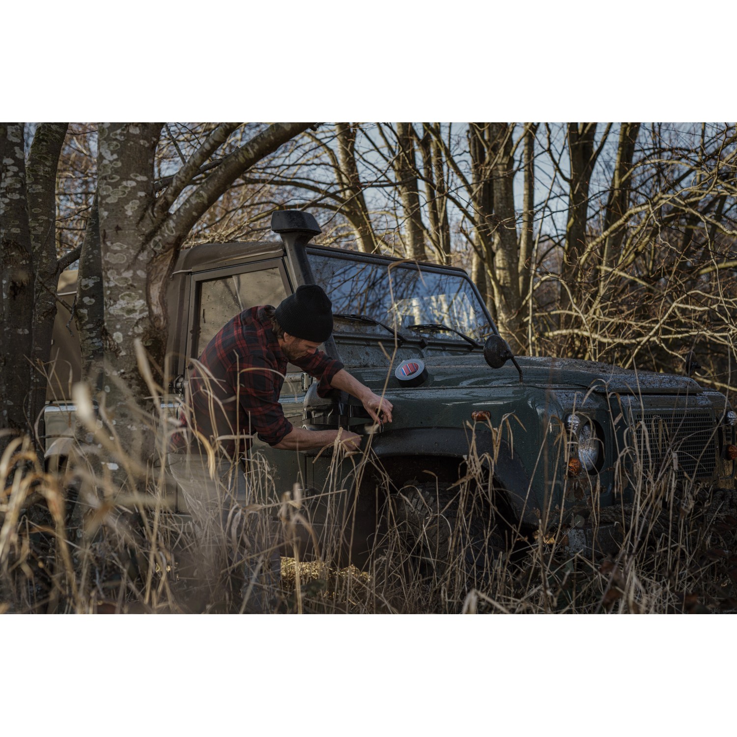 Mann repariert Auto mit Tesa Reparaturband Ultra Power Extreme im Outdoor-Einsatz.