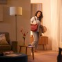 Philips WIZ E27 Lampe in Glühlampenform, warmweißes Licht in Wohnraum mit Frau.