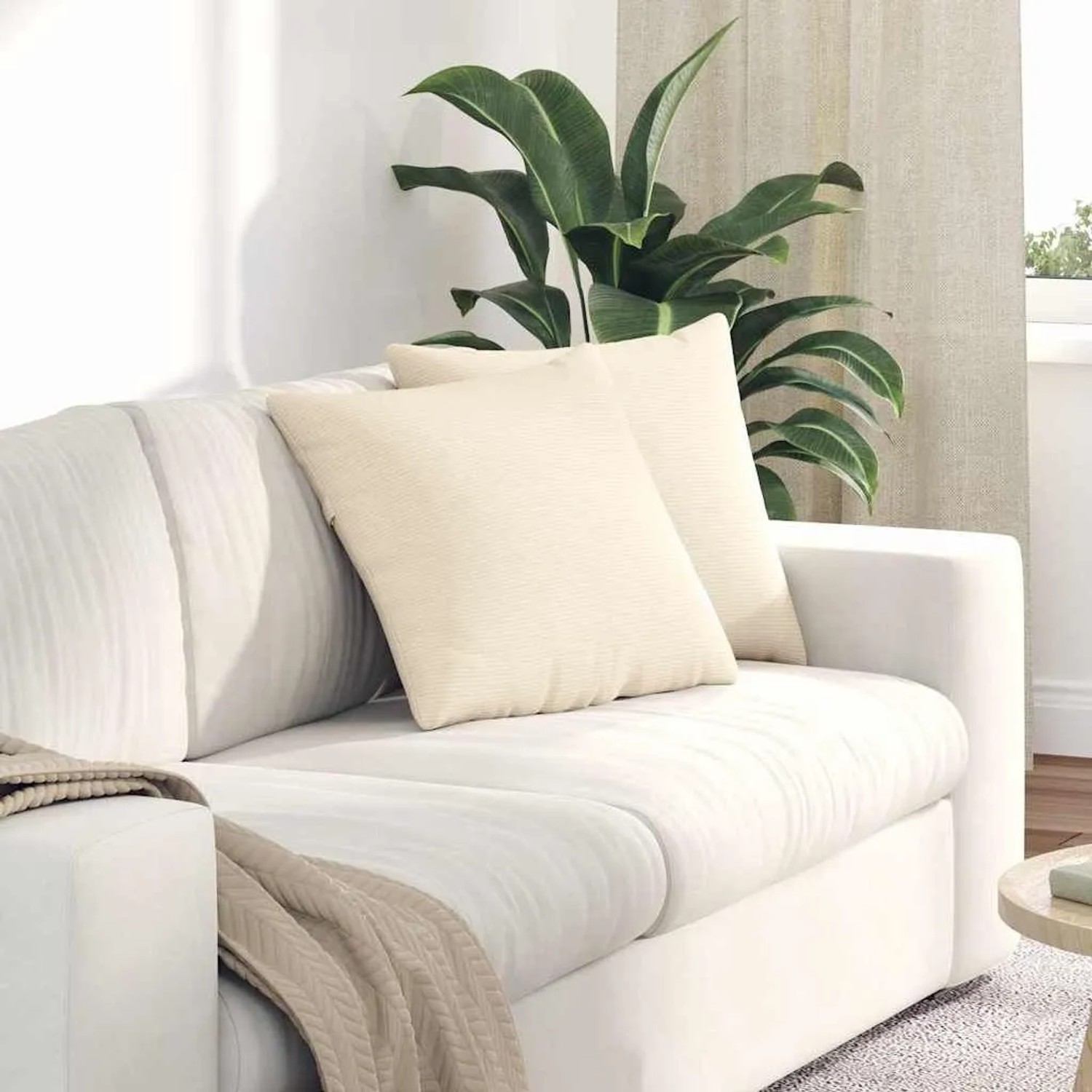 Zwei cremefarbene Sofakissen aus Cordstoff auf einem weißen Sofa im Wohnzimmer.